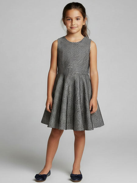 Young girl wearing a black and white patterned dress on a gray background
