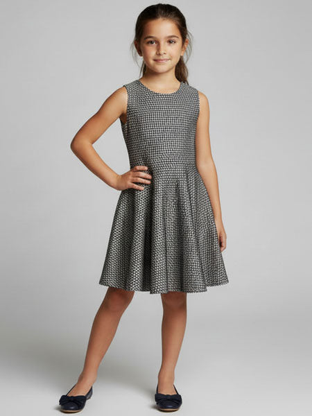 Young girl wearing a patterned dress on a plain background