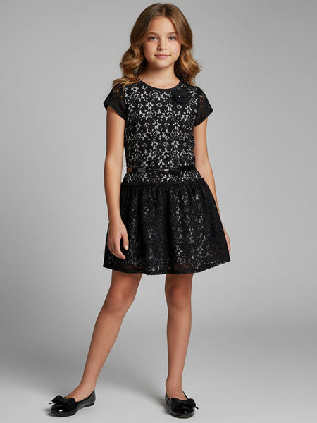Young girl wearing a black floral lace dress on a gray background