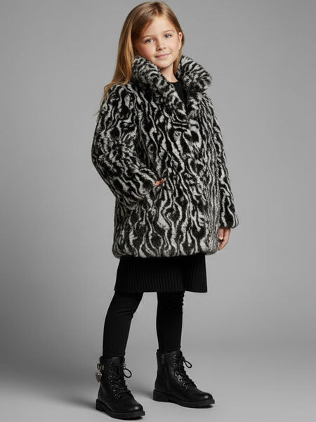 Child wearing a patterned coat on a gray background