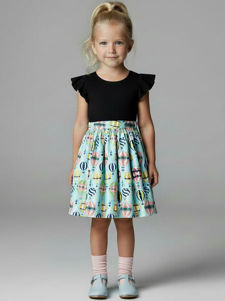 Young girl wearing a black top and colorful skirt  dresswith balloons on a gray background
