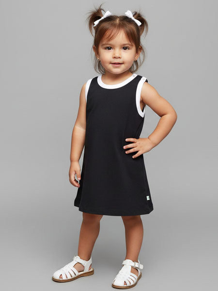 Young girl wearing a black dress with white trim on a gray background