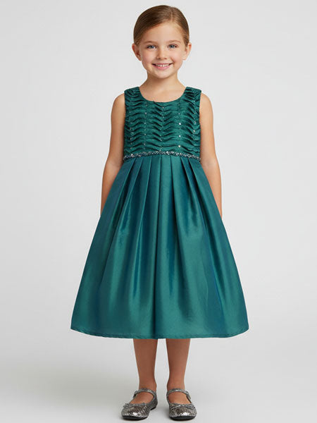Young girl wearing a teal green dress with a textured bodice on a white background