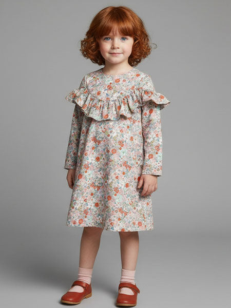Young girl wearing a floral dress with ruffled sleeves on a gray background