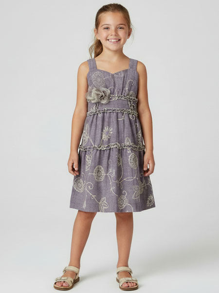 Young girl wearing a light plum patterned sleeveless dress on a white background