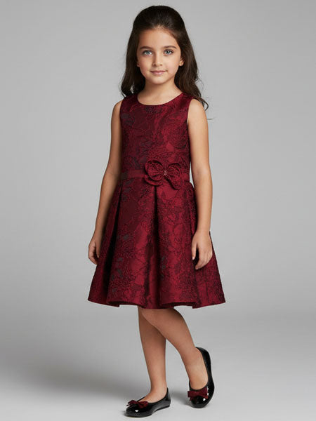 Young girl wearing a burgundy dress with a bow on a gray background