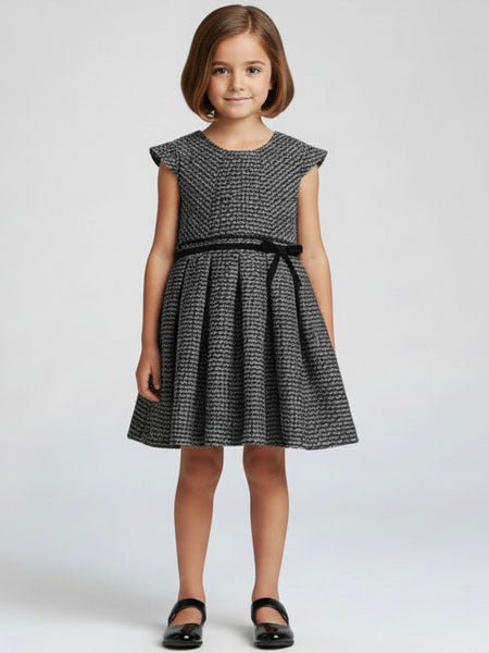 Young girl wearing a black and white patterned dress on a light gray background