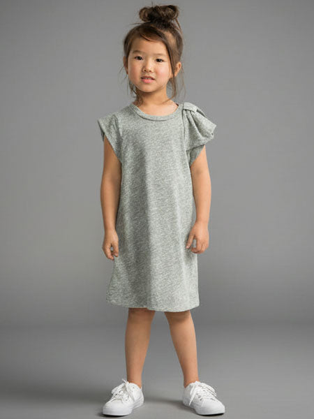 Young girl wearing a light gray dress with bow sleeves against a gray background
