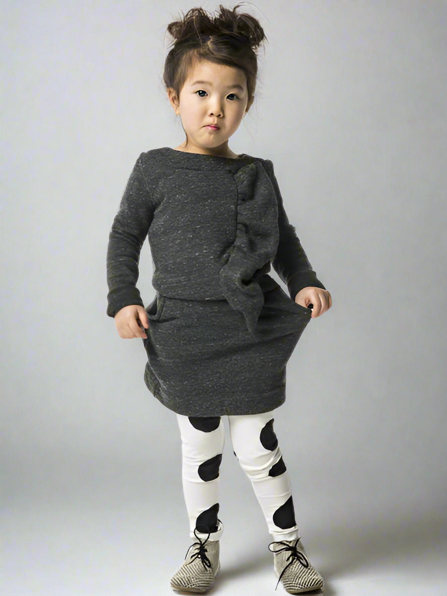 Child wearing a gray dress with ruffles on a white background