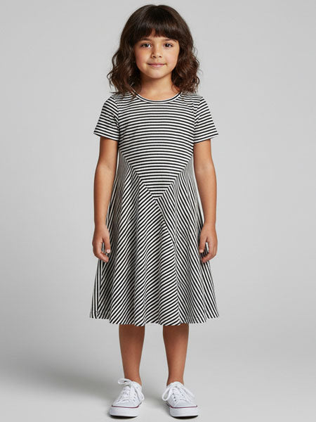 Young girl wearing a black and white striped dress on a gray background
