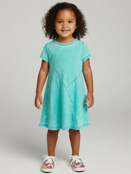 Young girl wearing a turquoise dress with colorful sneakers on a plain background