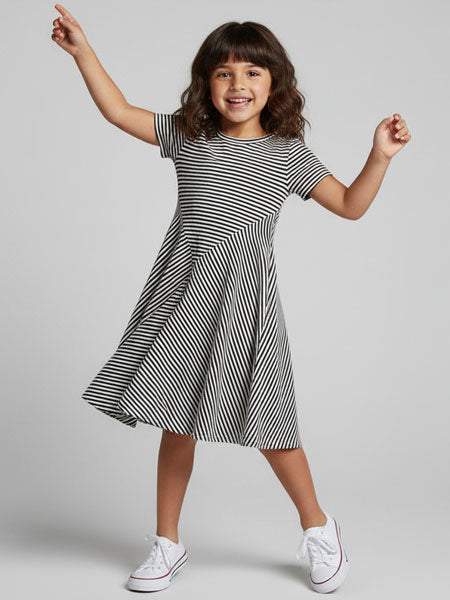Young girl wearing a black and white striped dress on a gray background