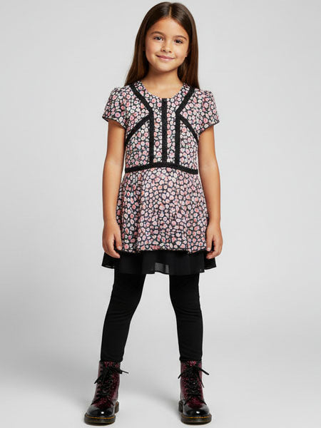 Young girl wearing a heart  patterned top and black pants on a white background