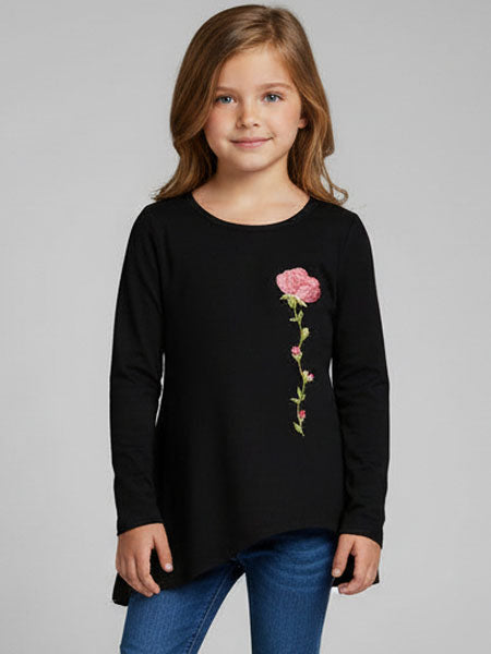 Young girl wearing a black long-sleeve shirt with a floral design on a gray background