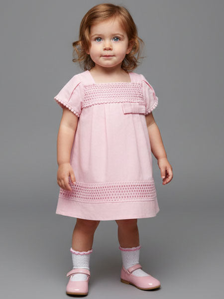 Young child wearing a pink dress against a gray background