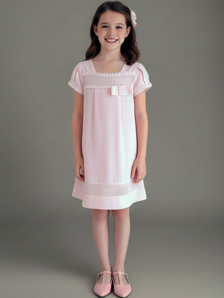 Young girl wearing a pink dress with lace details against a gray background