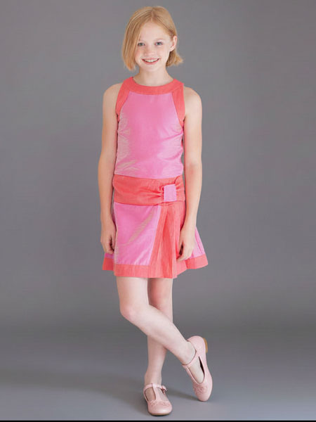 Young girl wearing a pink dress against a gray background