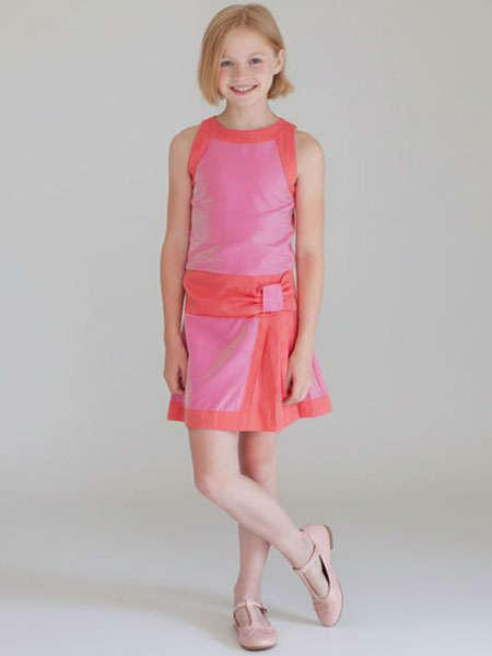 Young girl wearing a pink and orange dress against a plain background