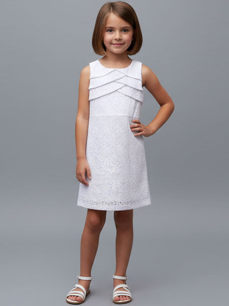 Young girl wearing a white dress against a gray background