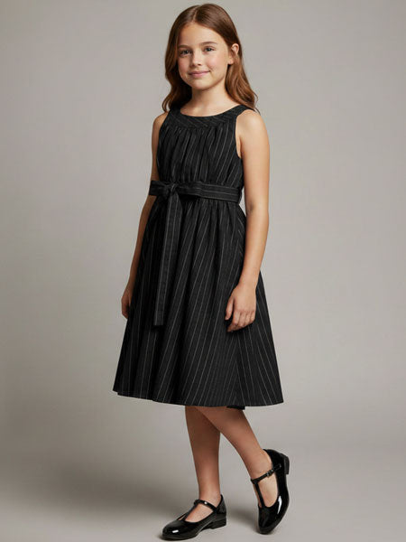 Young girl wearing a black pinstripe dress against a gray background