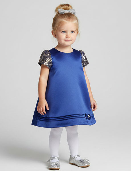 Young girl wearing a blue dress with sequin sleeves on a white background
