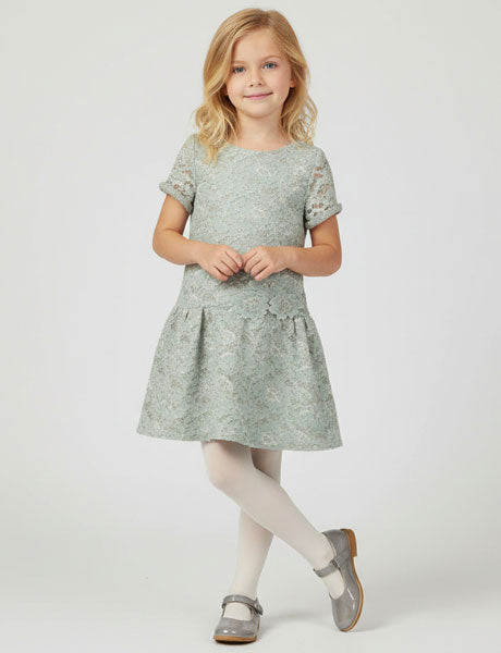 Young girl wearing a light gray dress with lace details on a white background