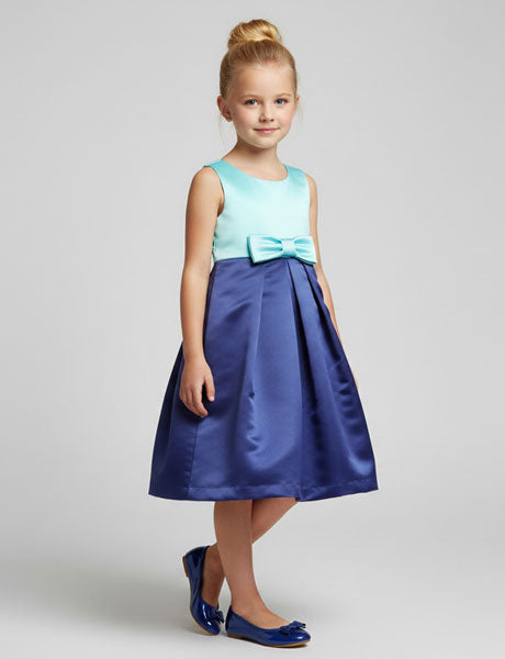 Young girl wearing a blue and green dress with a bow on a gray background