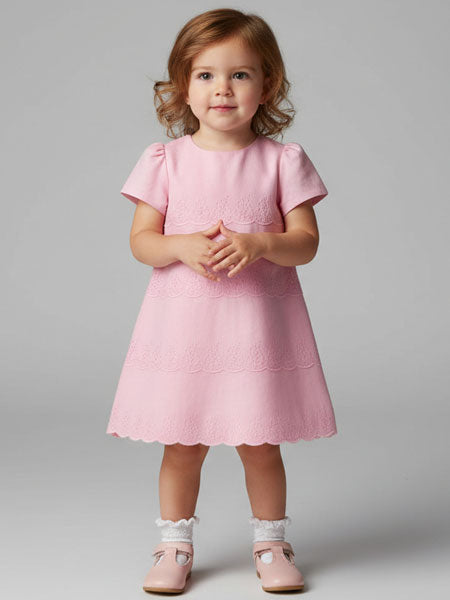 Young girl wearing a pink dress against a gray background