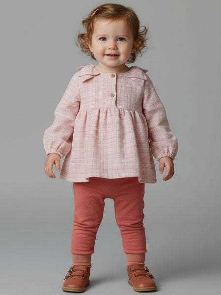 Child wearing a pink checkered top and red pants on a gray background
