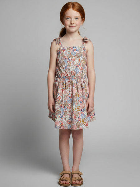 Young girl wearing a floral dress against a plain background