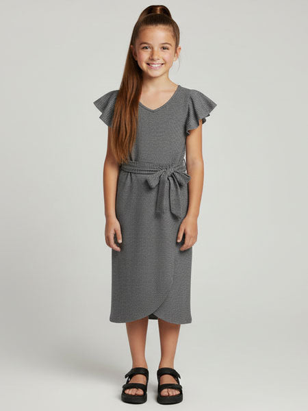 Young girl wearing a gray dress with ruffled sleeves on a plain background