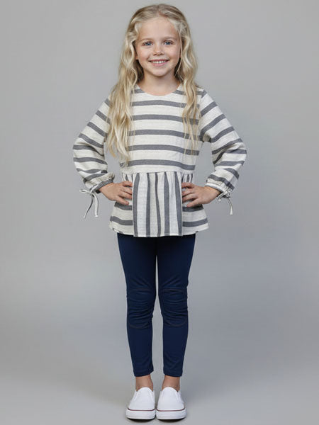 Young girl wearing a striped top and navy pants on a gray background