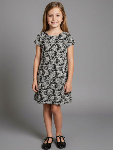 Young girl wearing a black and white patterned dress against a gray background