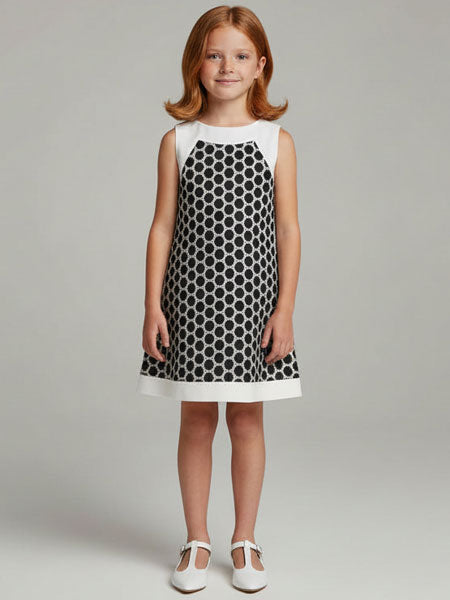 Young girl wearing a black and white polka dot dress on a gray background