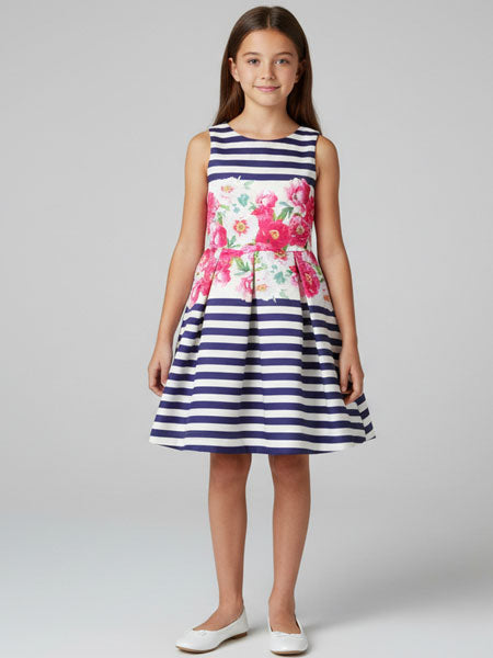 Young girl wearing a dress with floral pattern and blue stripes on a plain background