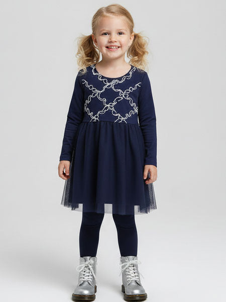 Young girl wearing a navy dress with lace details on a white background
