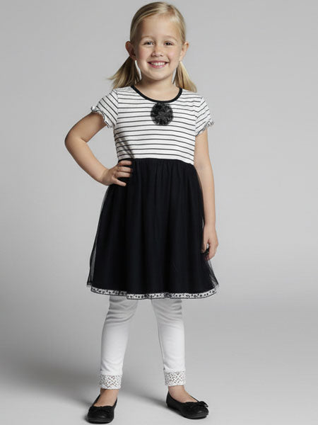 Young girl wearing a black and white dress with a gray background