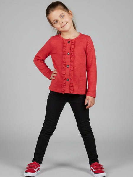 Child wearing a red jacket and black pants on a gray background