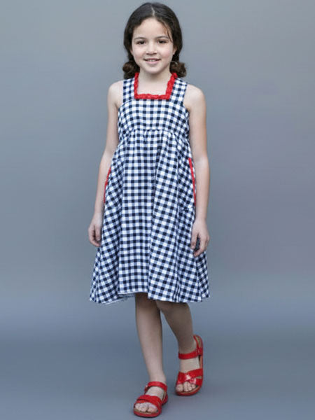 Young girl wearing a checkered dress with red accents against a gray background