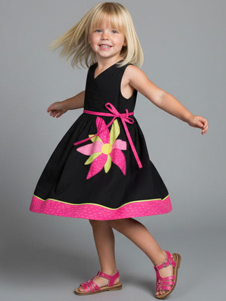 Young girl wearing a black dress with pink floral design and trim on a gray background