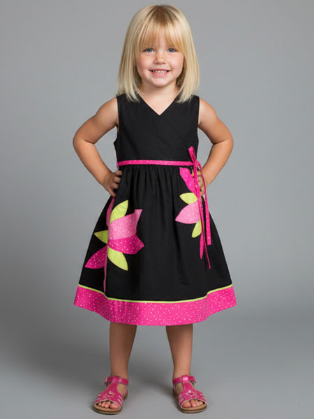 Young girl wearing a black dress with pink floral accents on a gray background
