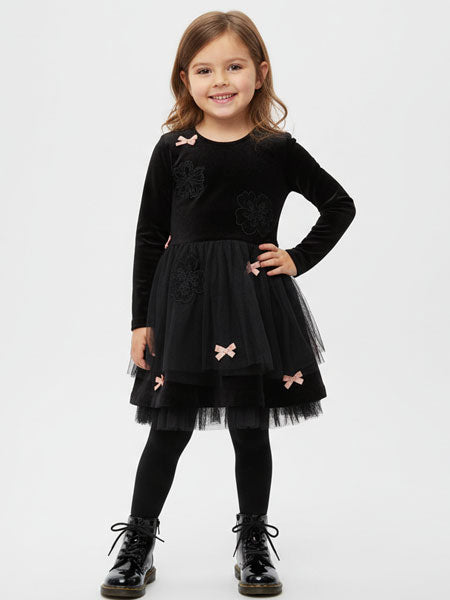 Young girl wearing a black dress with pink bows on a white background