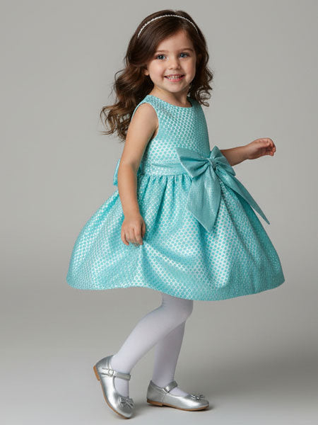 Young girl wearing a turquoise dress with a large bow on a gray background