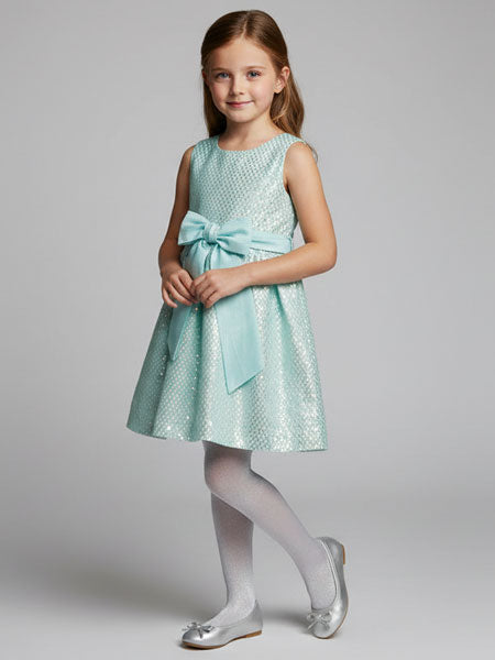 Young girl wearing a light blue sequin dress with a bow on a gray background
