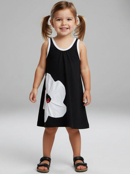 Young girl wearing a black dress with a white flower design on a gray background