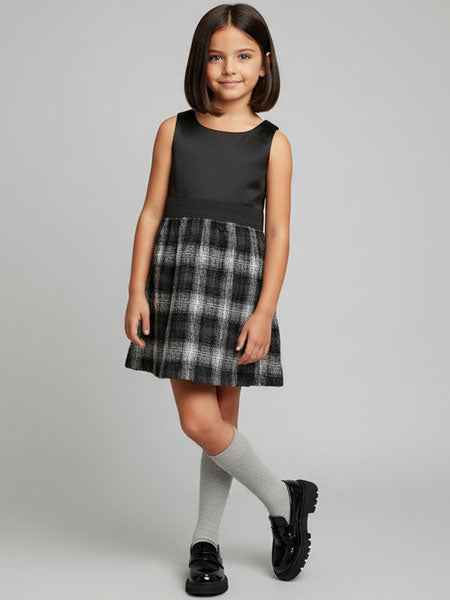 Young girl wearing a black and gray plaid dress on a gray background
