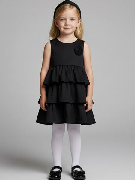 Young girl wearing a black dress with a flower detail on a gray background