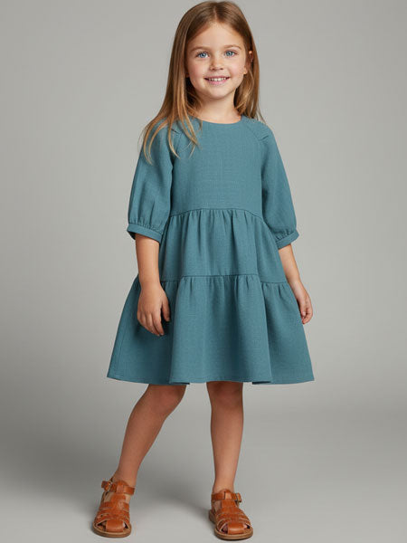 Young girl wearing a teal dress on a gray background