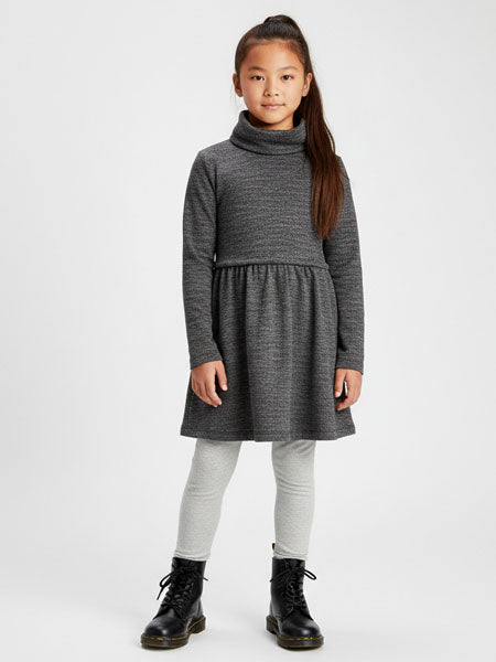 Young girl wearing a gray dress with a turtleneck on a white background