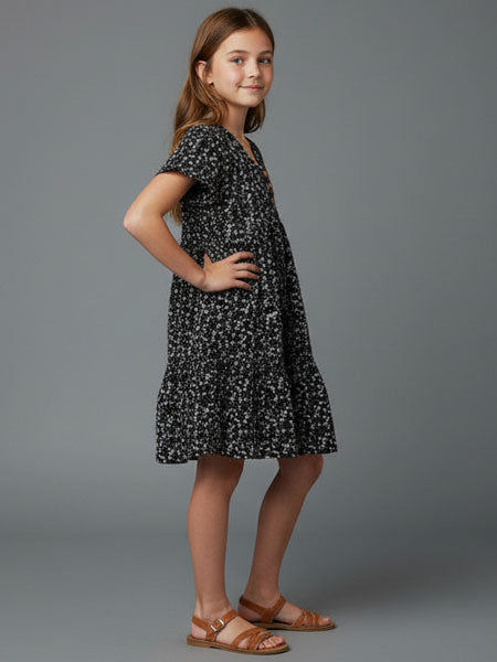 Young girl wearing a black floral dress on a gray background